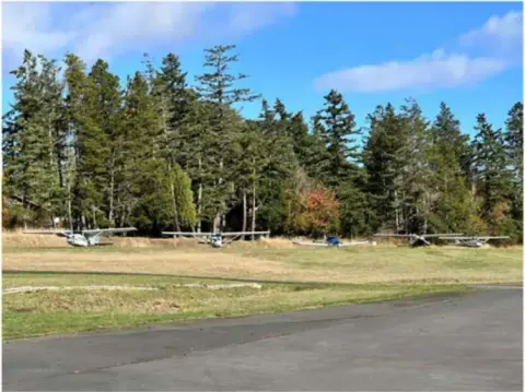 Fly-out airplanes parked in a row on the grass at Roche Harbor