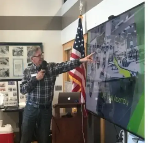 Presenter pointing at a large screen during the October presentation