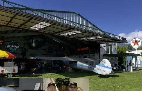 Airplanes and visitors under the open front of a hangar