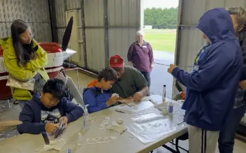 Kids and adults building model gliders at a workshop table