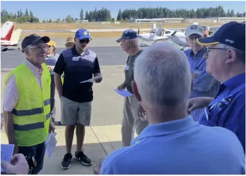 Pilots and volunteers in safety vests gathered on the ramp