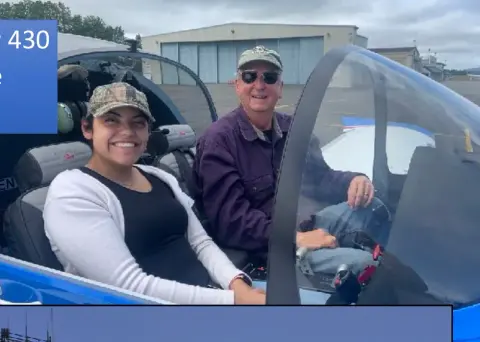 Smiling pilot and young passenger in the cockpit of a blue airplane