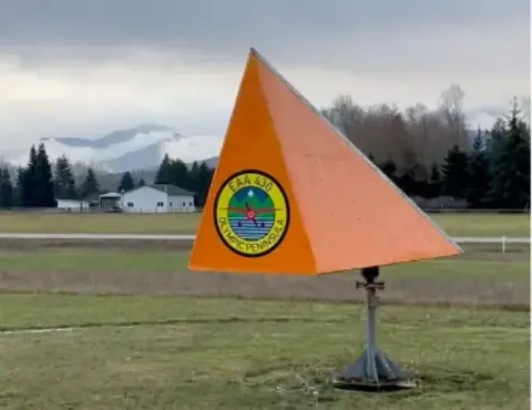 Orange wind tetrahedron mounted on a pole beside an airfield