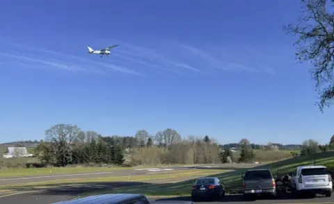 Small airplane flying low over a grass airfield