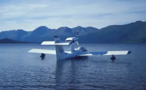 A white amphibian airplane on calm water with mountains behind