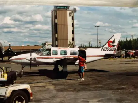 Twin-engine airplane parked near a control tower
