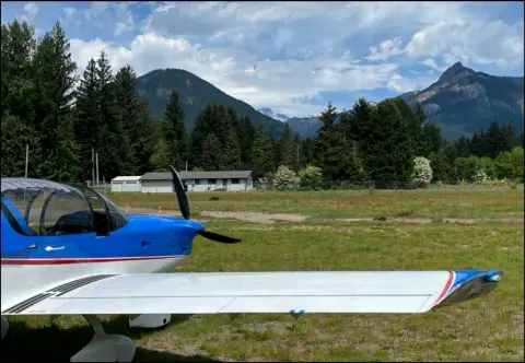 A blue Sling 2 on the grass with mountains behind