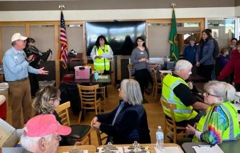Ray Ballantyne speaking to volunteers and families in a meeting room