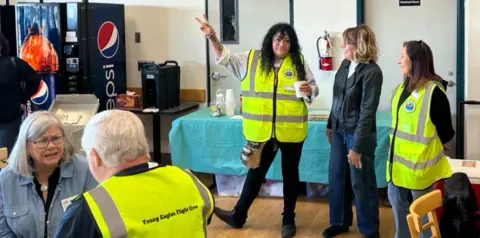 Volunteers in yellow safety vests gathered in the meeting room before the rally