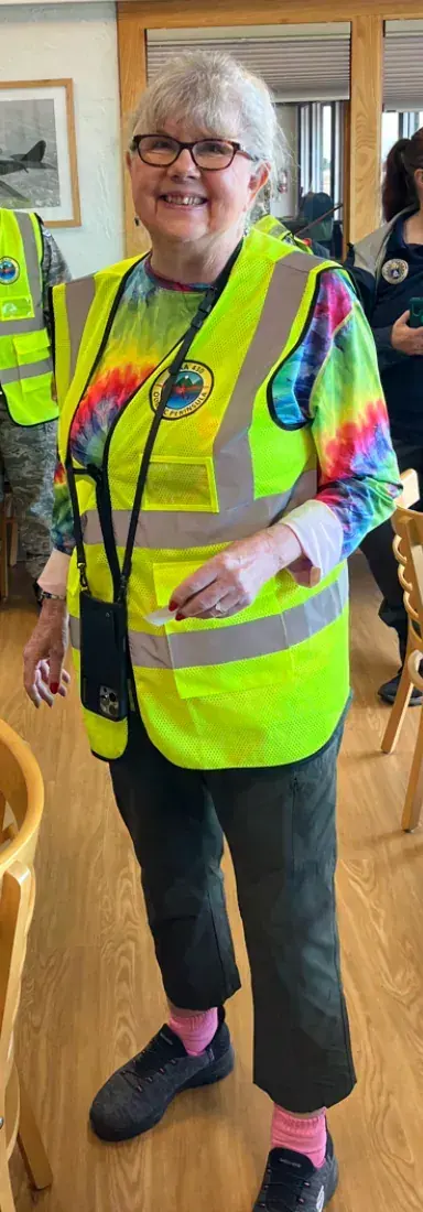 A volunteer in a bright yellow safety vest smiling in the meeting room