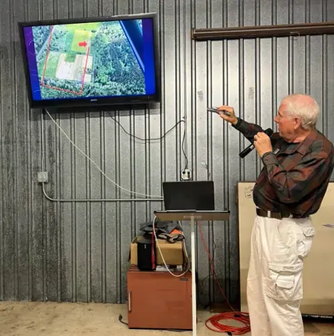 Presenter speaking to members in a hangar