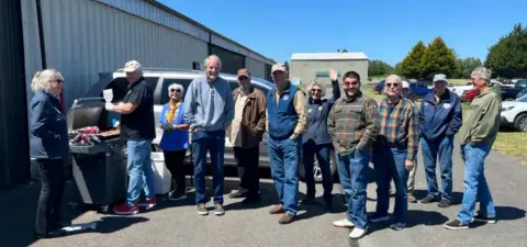 Members standing together outside a hangar