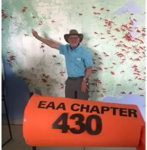 Man pointing at a large map beside an orange EAA Chapter 430 sign