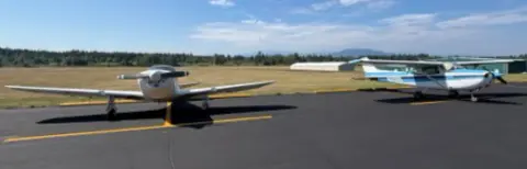 Two airplanes parked on the ramp under a clear blue sky