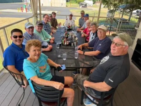 Smiling members around an outdoor table at lunch