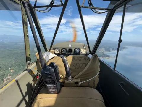Handheld radio clipped in the front seat of the Piper L-4H cockpit