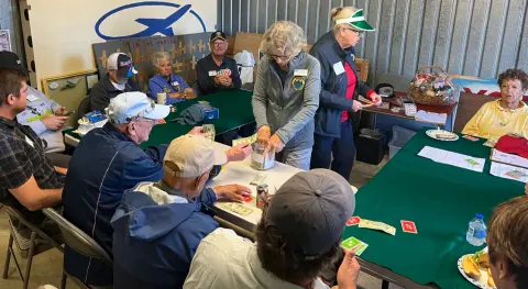 Members playing the Poker Run card games at tables in the hangar