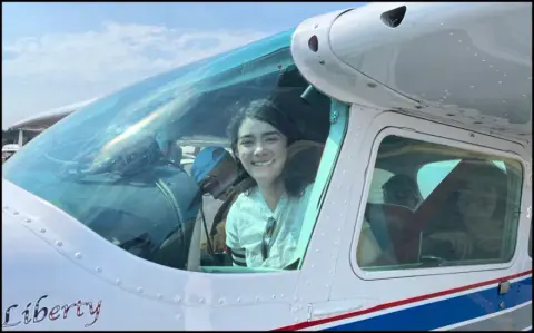 Jazmin Stamper smiling in the left seat of a white high-wing Cessna