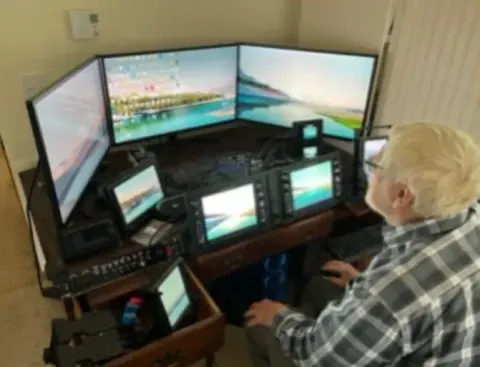 A man seated at a flight simulator with several screens
