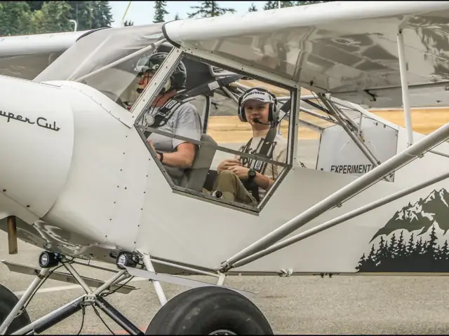 Ernie Hansen and a Young Eagle wearing headsets in his Super Cub