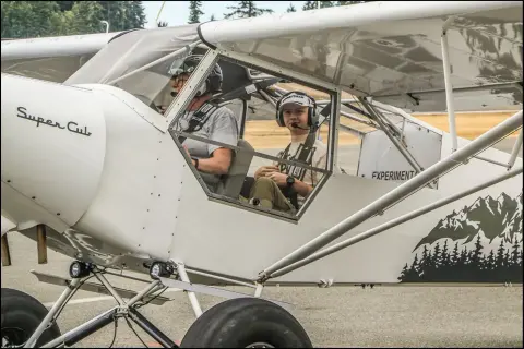 Ernie Hansen and a Young Eagle wearing headsets in his Super Cub
